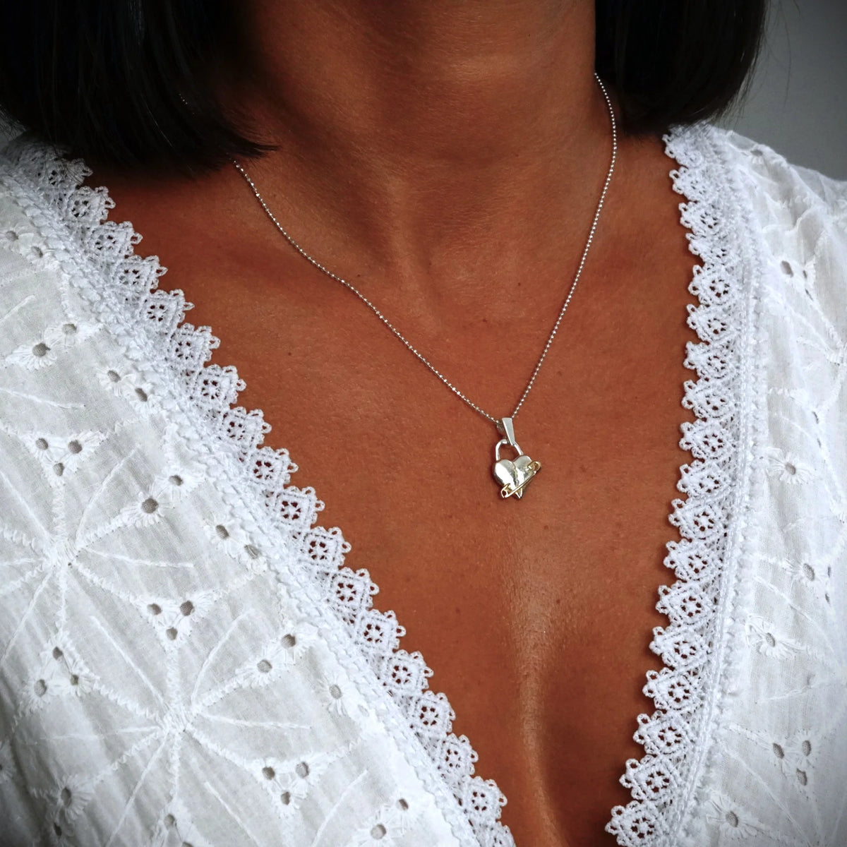 „Verletztes Herz“-Anhänger aus 925er Silber mit goldfarbenem Sicherheitsnadel-Akzent – Symbol für erlebten Schmerz und bleibende emotionale Spuren, Skulpturenschmuck im Boho- und rustikalen Stil | Art Diva