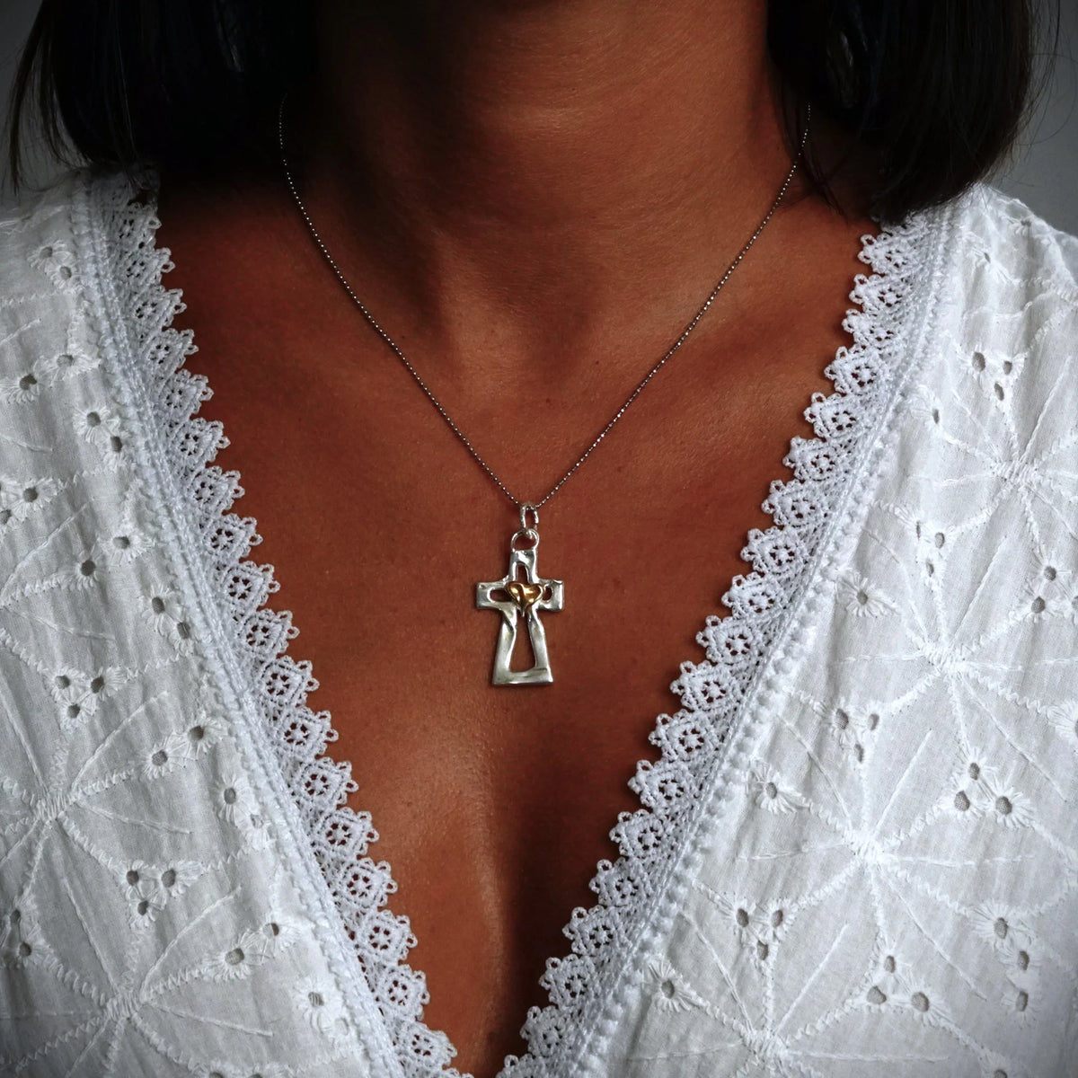 Kreuz-Anhänger mit Herz aus 925er Silber und goldfarbenen Akzenten – Skulpturenschmuck als Symbol für Glauben und Liebe | Art Diva