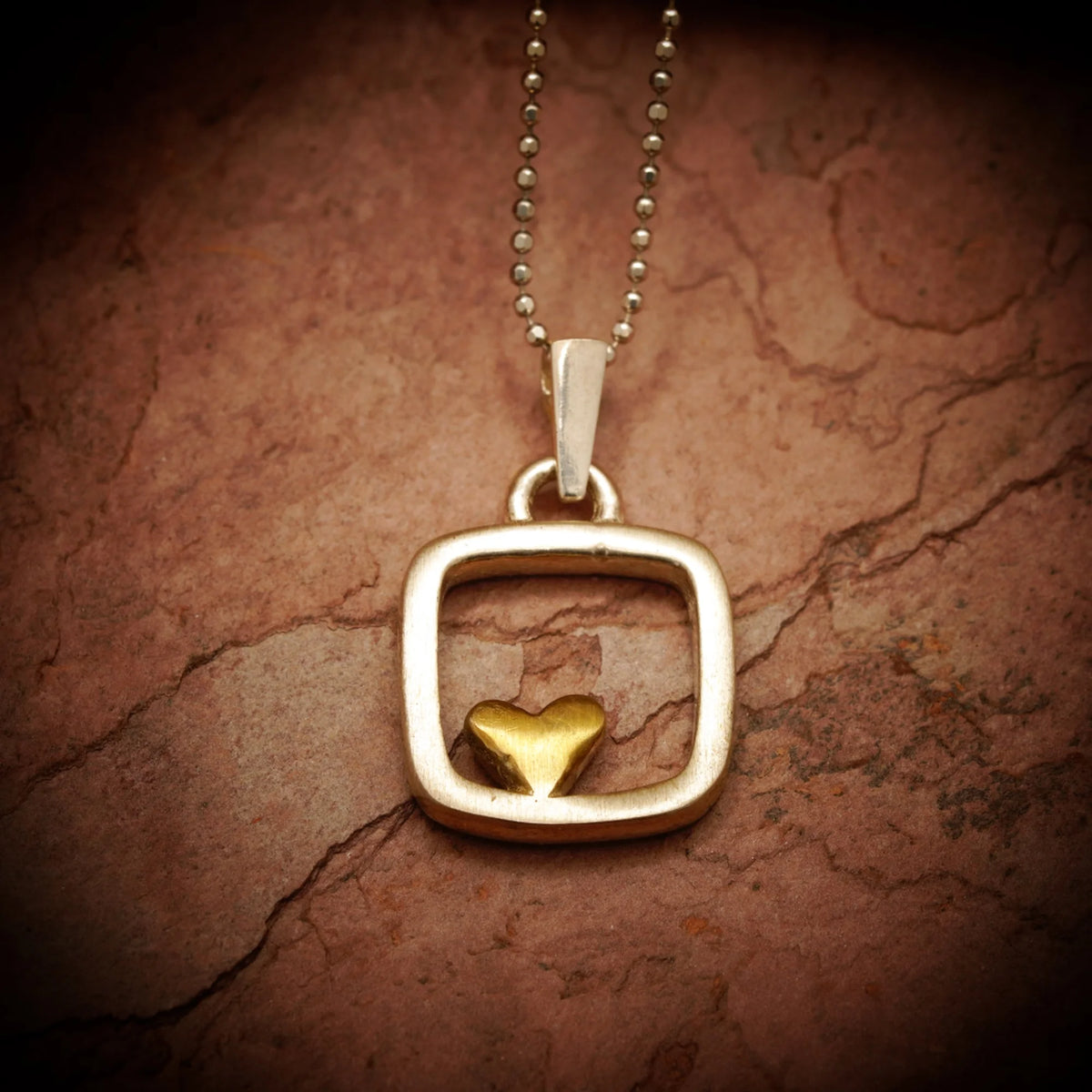 „Herz im Quadrat“ – handgefertigter Anhänger aus 925er Silber mit goldfarbenen Akzenten, Talisman für Liebe und Ausgeglichenheit, Skulpturenschmuck im Boho- und rustikalen Stil | Art Diva