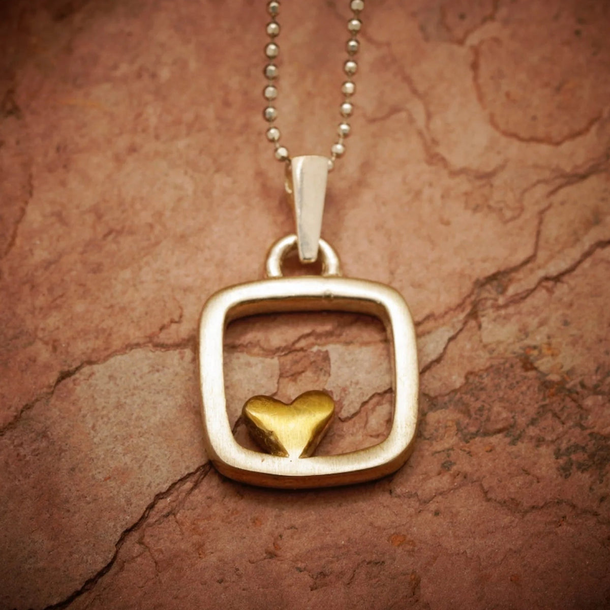 „Herz im Quadrat“ – handgefertigter Anhänger aus 925er Silber mit goldfarbenen Akzenten, Talisman für Liebe und Ausgeglichenheit, Skulpturenschmuck im Boho- und rustikalen Stil | Art Diva