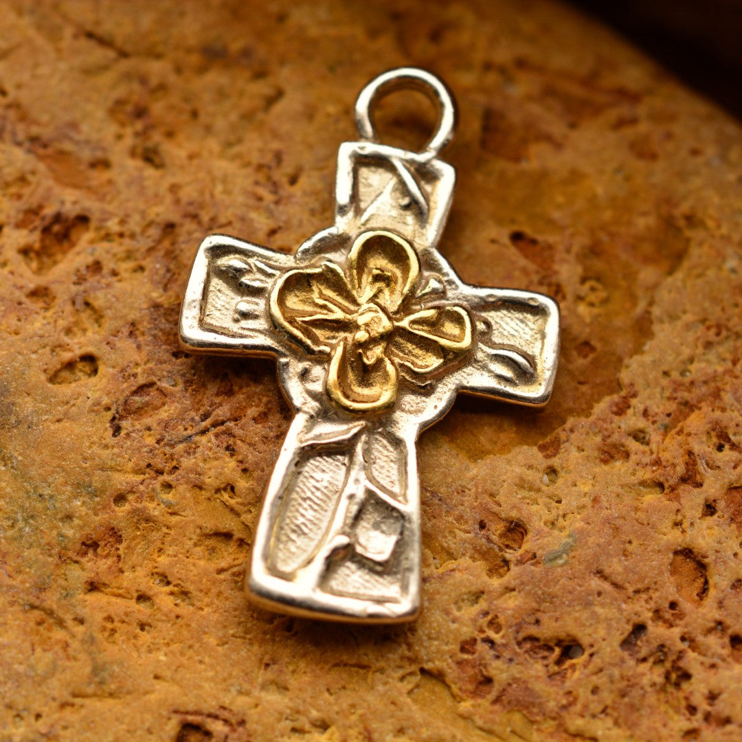 Сребърен медальон 925 „Кръст с цвете“ със златни акценти – ръчно изработен талисман на вярата и духовната сила, амулет на вътрешния мир и закрилата, бохо-рустик скулптурно бижу от Арт Дива, заснето върху каменен фон.
