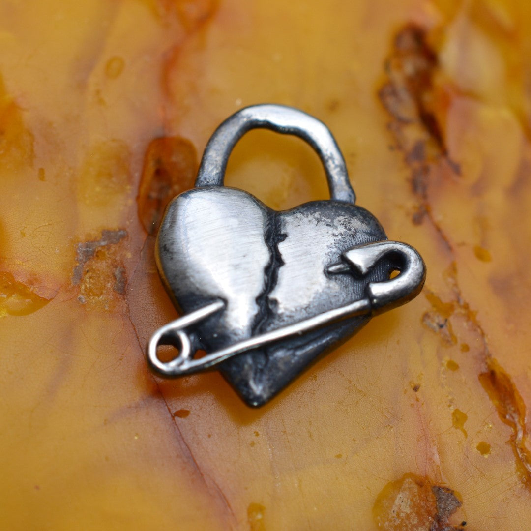 „Geflicktes Herz“-Anhänger aus 925er Silber mit Sicherheitsnadel – Symbol für erlebten Schmerz und bleibende emotionale Spuren, oxidierter Skulpturenschmuck im Boho- und rustikalen Stil | Art Diva