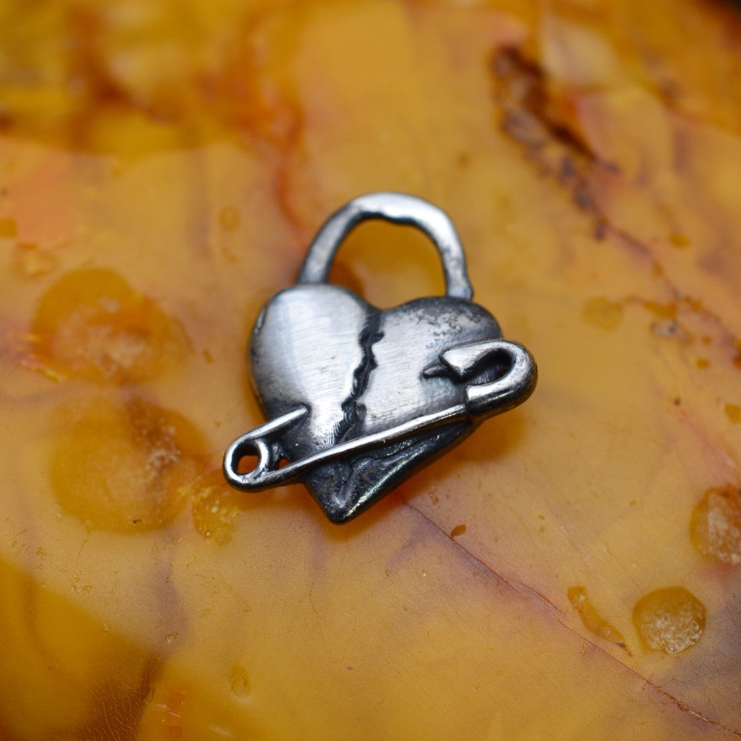 „Geflicktes Herz“-Anhänger aus 925er Silber mit Sicherheitsnadel – Symbol für erlebten Schmerz und bleibende emotionale Spuren, oxidierter Skulpturenschmuck im Boho- und rustikalen Stil | Art Diva
