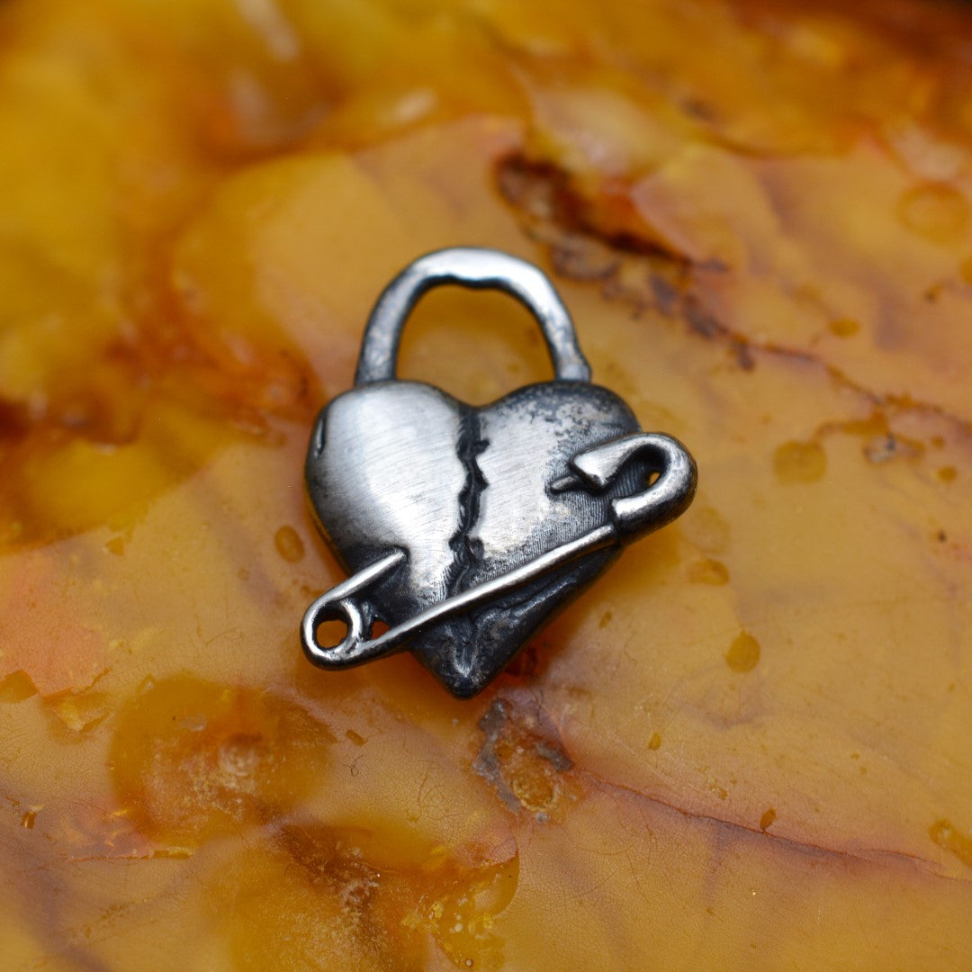 „Geflicktes Herz“-Anhänger aus 925er Silber mit Sicherheitsnadel – Symbol für erlebten Schmerz und bleibende emotionale Spuren, oxidierter Skulpturenschmuck im Boho- und rustikalen Stil | Art Diva